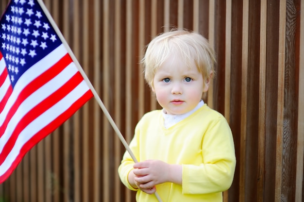 Cute toddler boy holding american flag. 