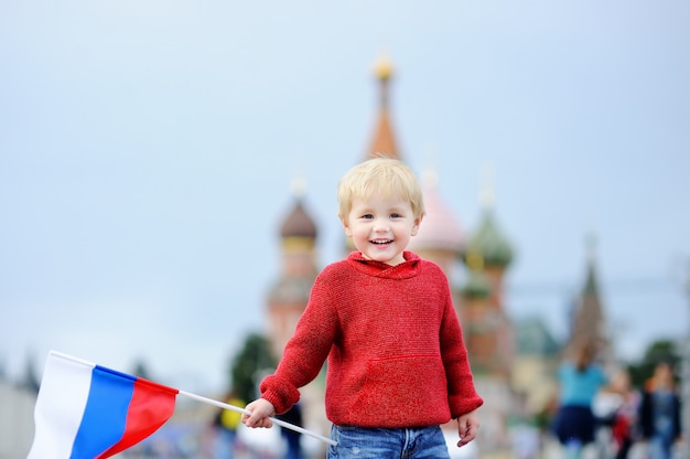 Cute toddler boy holding russian flag with Red Square and Vasilevsky descent 