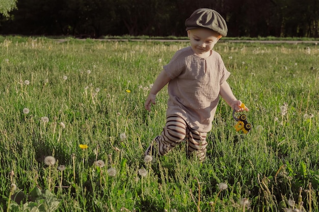 Cute toddler boy walking on grass meadow in countryside