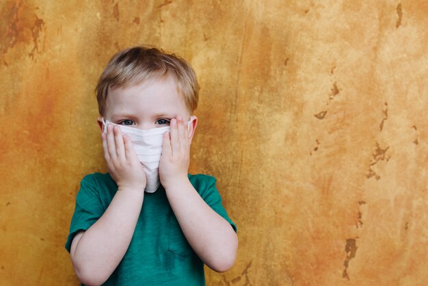 Cute toddler boy wearing protective medical face mask