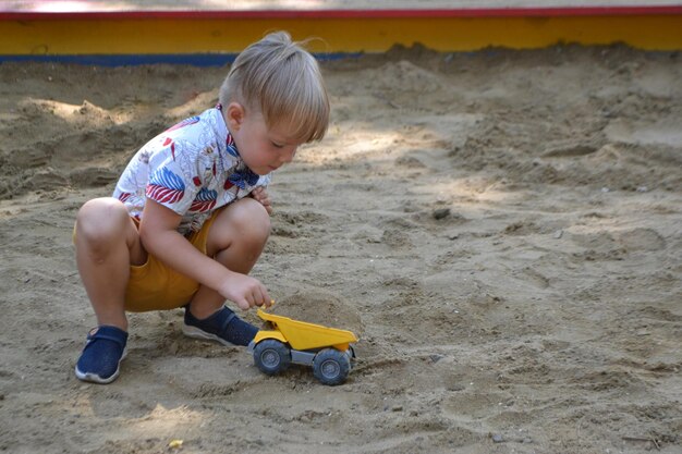 Cute toddler boyl playing in sand on outdoor playground