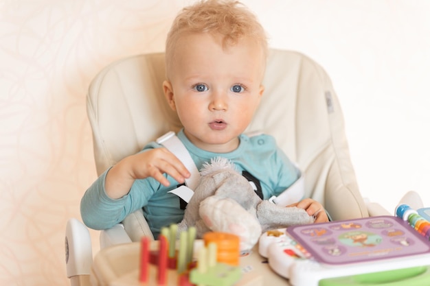 Cute toddler child eating piece of cake and drinking juice at home