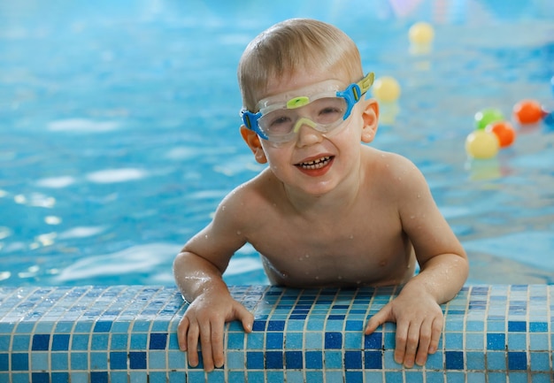 Cute toddler child near pool side smiling in googles after swimming