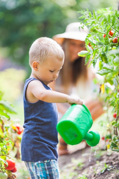 Cute toddler helphing mom in the garden
