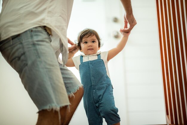 Foto bambino carino bambino concetto di famiglia bambino che impara a camminare con il padre e la madre per aiutare a prendersi cura e tenendo la mano il primo passo con l'infanzia sostegno genitore piccolo amore ritratto ragazzino a casa