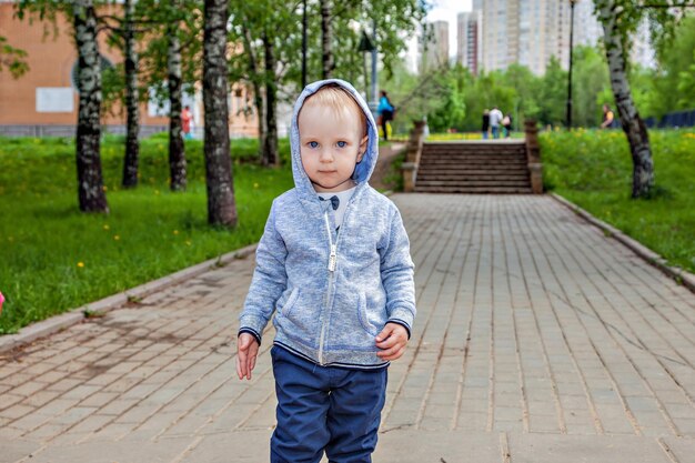 写真 春の晴れた日に遊び場で遊ぶかわいい幼児。散歩にスマートな陽気な少年。