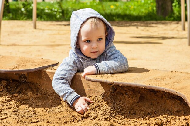 写真 春の晴れた日に砂場の遊び場で遊ぶかわいい幼児。