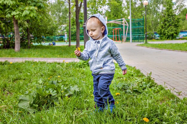 Bambino sveglio che gioca nel parco giochi in giornata di sole primaverile. ragazzo divertente seduto su un'altalena