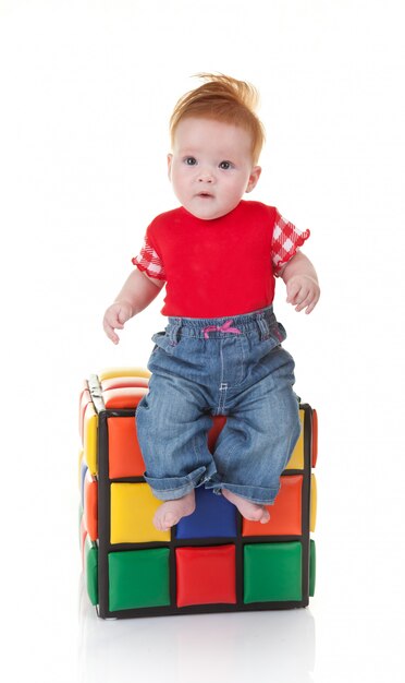 Cute toddler sitting on colorful cube