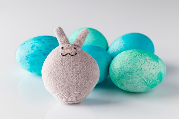 Cute toy easter bunny and blue painted eggs with feathers  