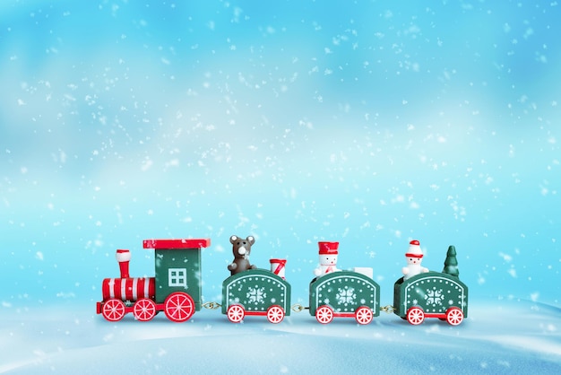 Cute train in the snow Christmas New Year background Wooden toy with a bear and two snowshoes