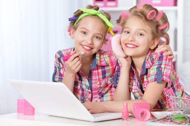 Cute  tweenie girls  in hair curlers  with laptop at home