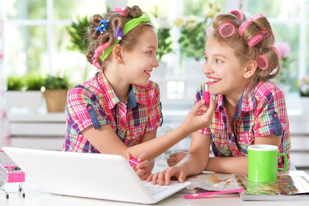 Cute  tweenie girls  in hair curlers  with laptop at home