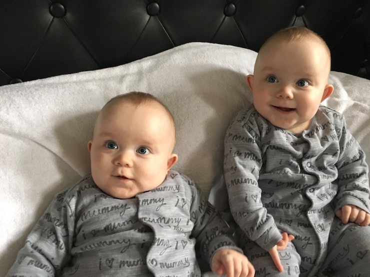 Photo cute twins sitting on bed at home