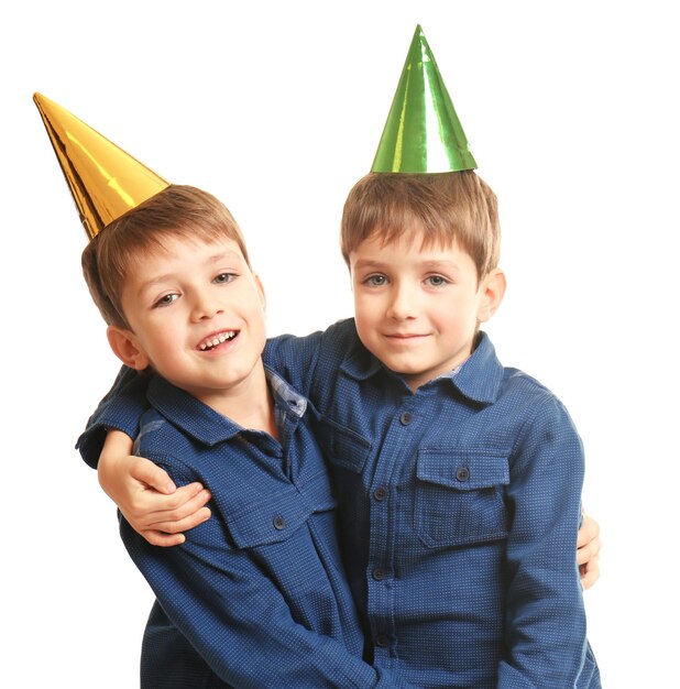 Photo cute twins with birthday hats on white background