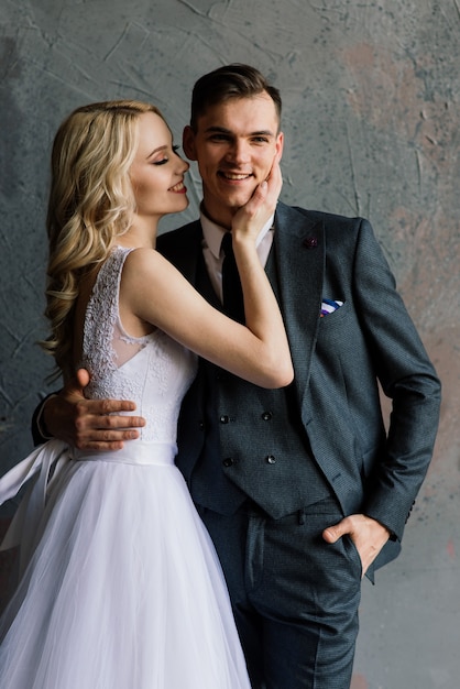 Cute wedding couple in the interior of a classic studio decorated. They kiss and hug each other.