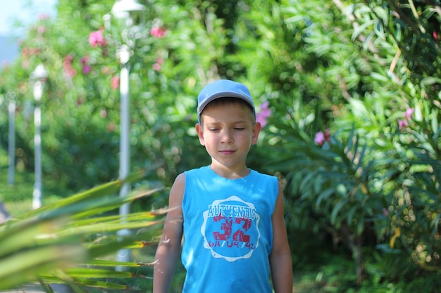 夏服を着たかわいい白人の男の子が公園でポーズをとる Tシャツを着た少年モデル 子供の夏のファッション