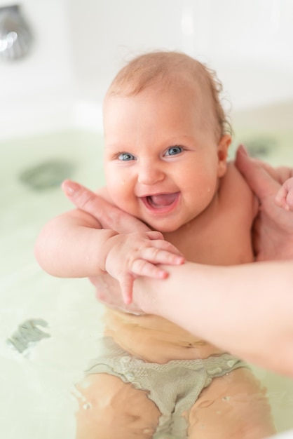 Cute woman bathes her smiling toddler in the bathroom