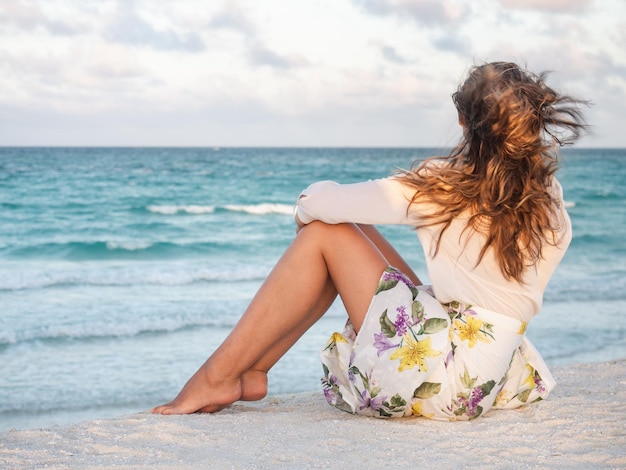 Cute woman on the beach against the background of the sea