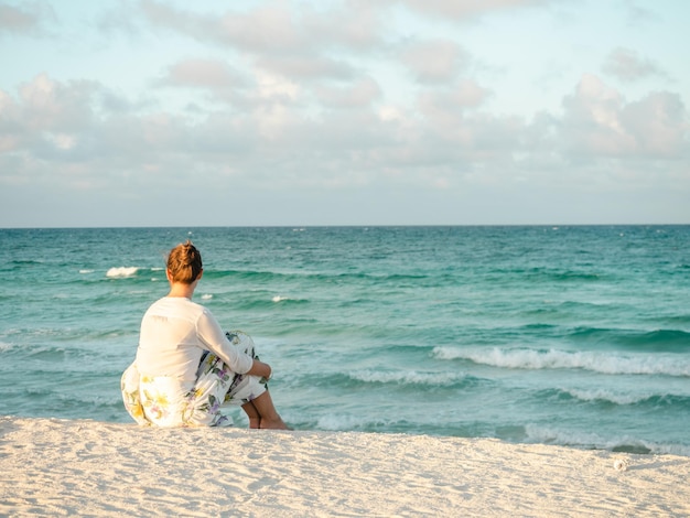 Cute woman on the beach against the background of the sea