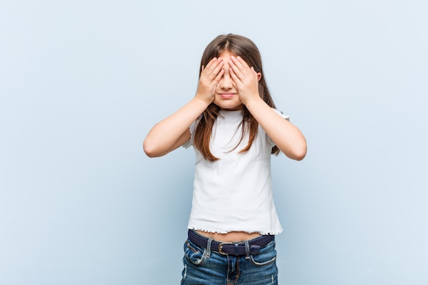 Cute woman covers eyes with hands, smiles broadly waiting for a surprise.