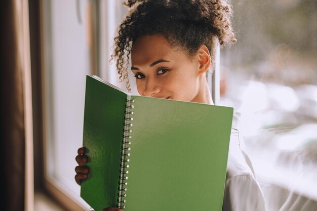 Cute woman. Cute young mulatta holding a notebook and smiling