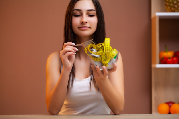 Cute woman on a diet holding a plate full of tape