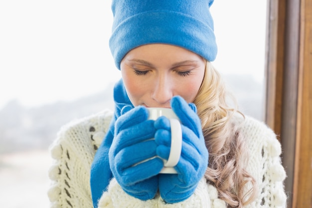 Donna carina che beve caffè in vestiti caldi