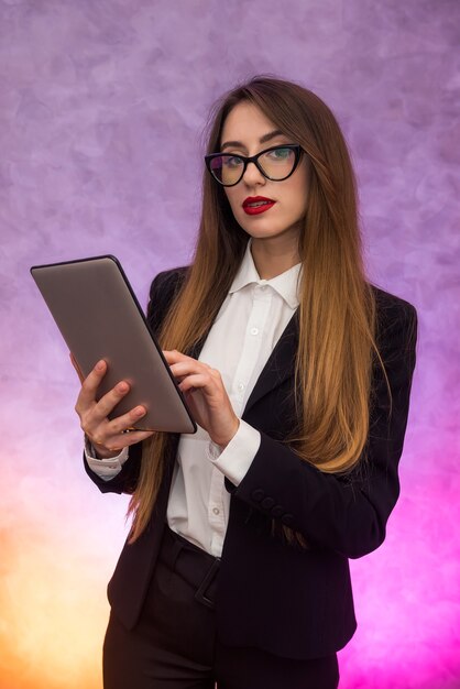 Cute woman in glasses using tablet on abstract background. Business concept