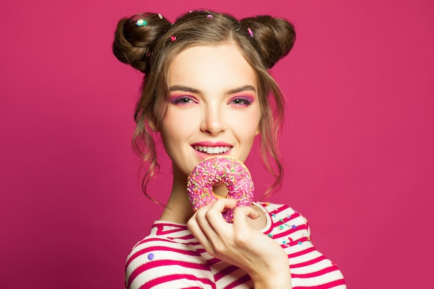 Милая женщина с пончиком на ярко-желтом фоне концепция диеты