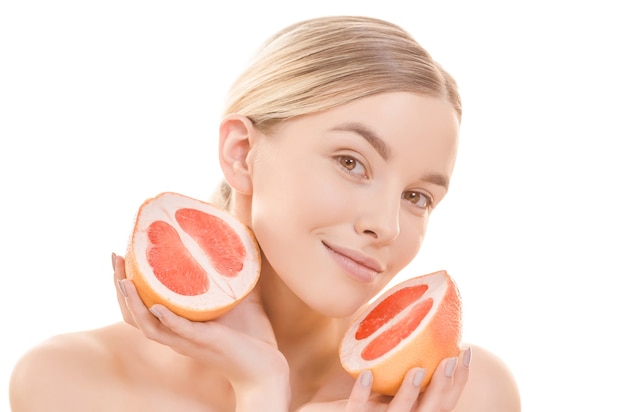 The cute woman holding a grapefruit on the white background