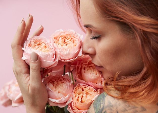 Cute woman is sniffing a bouquet of pink buttercup asian