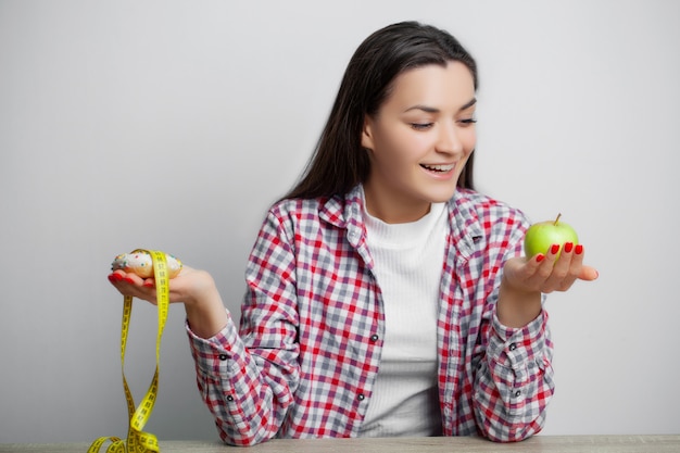 Cute woman makes a choice between healthy and harmful food