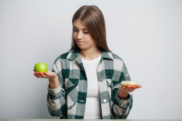 Cute woman makes a choice between healthy and harmful food
