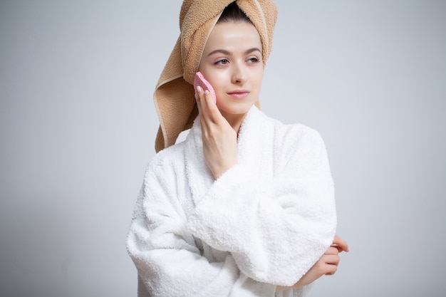 La donna carina fa il trucco per il viso in bagno