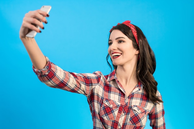 The cute woman makes a selfie on the blue background