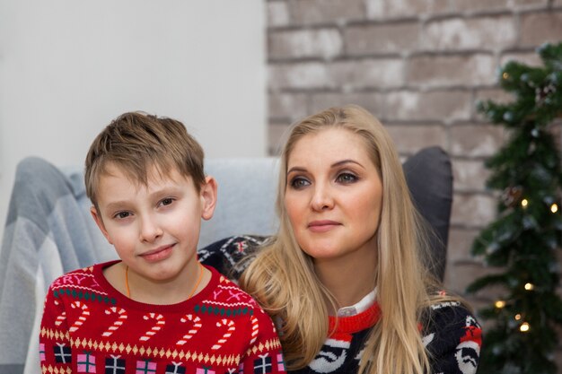 Cute woman mother with child boy sitting in a chair in Christmas clothes New Years concept