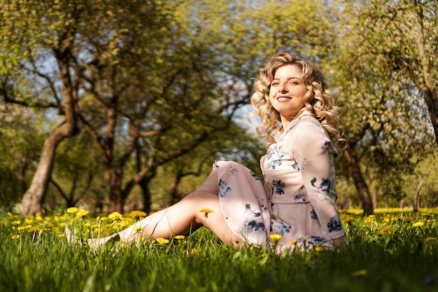 Cute woman rest in the green summer park with dandelions