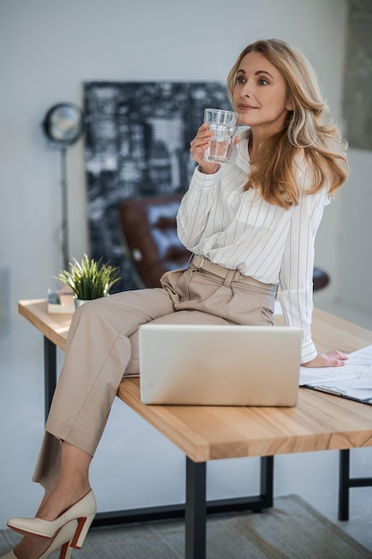 A cute woman sitting on the table in the offcie