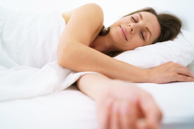 Premium Photo | Cute woman sleeping in bed and smiling at camera