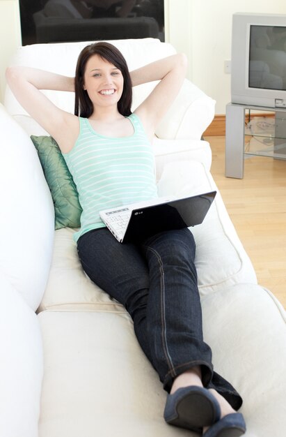 Cute woman surfing the internet lying on a sofa