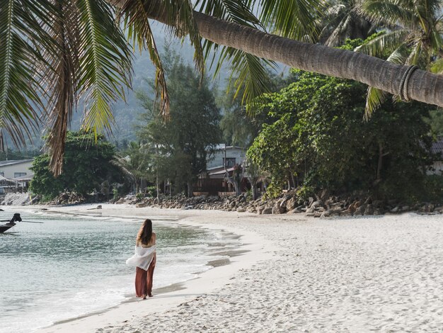 Cute woman walking along a stunning white sandy beach