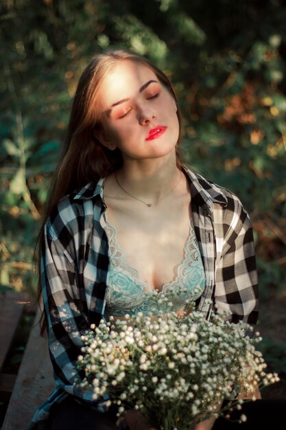 A cute woman with a bouquet of wildflowers under the sun's rays Portrait in nature