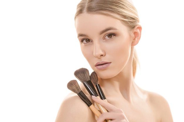 The cute woman with cosmetic brushes on the white background