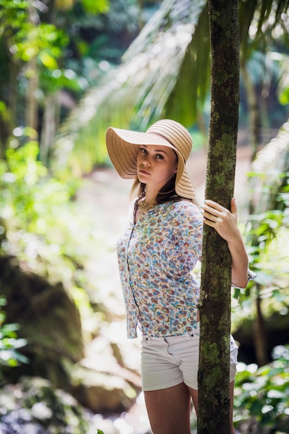 Donna sveglia con un cappello che posa nella foresta