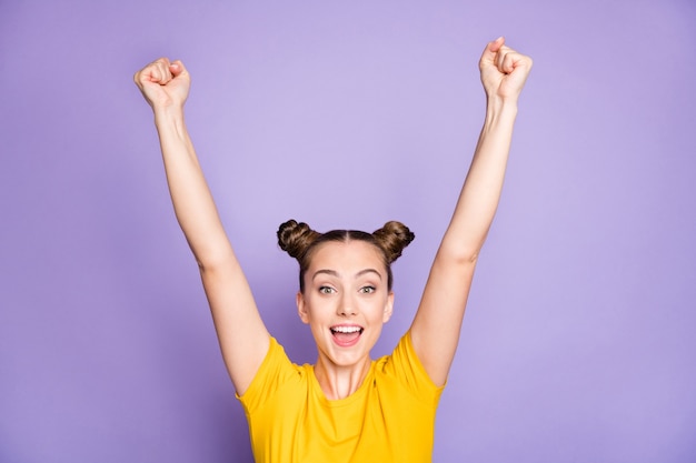 Cute woman with topknots posing against the purple wall