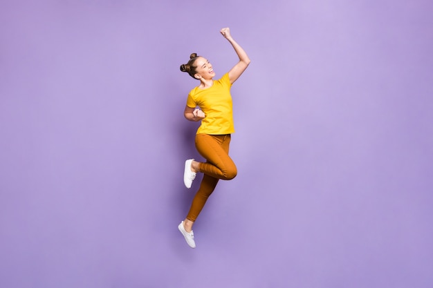 Cute woman with topknots posing against the purple wall