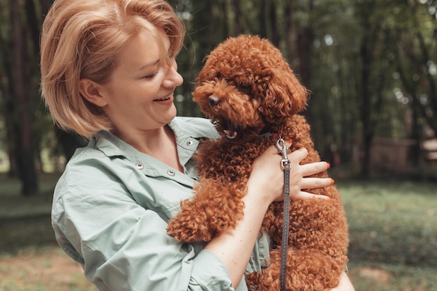 女性の所有者の腕の中でかわいいあくび犬