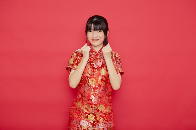 Симпатичная молодая азиатская женщина носит Cheongsam с действием для концепции китайского нового года