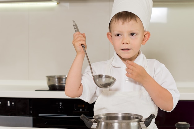 Cute young chef tasting his cooking